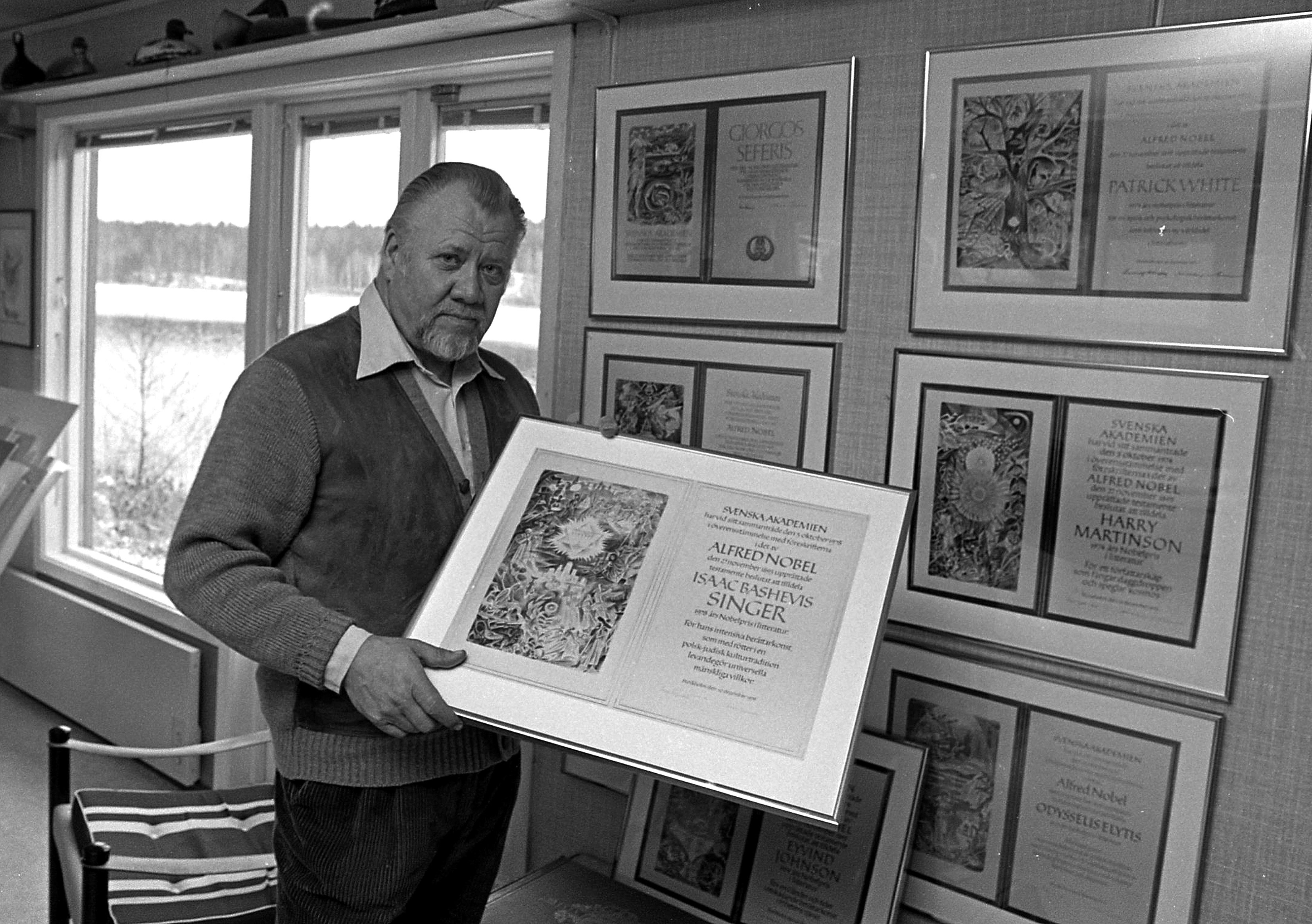 Gunnar Brusewitz står i sin atelje. På väggen syns ett antal Nobeldiplom och i handen håller han ett.