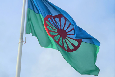 Bild på romska flaggan med himlen i bakgrunden.