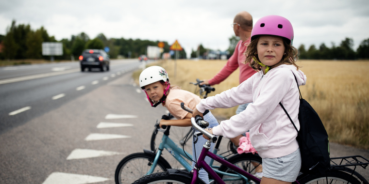 barn och vuxen med cyklar på väg över landsväg