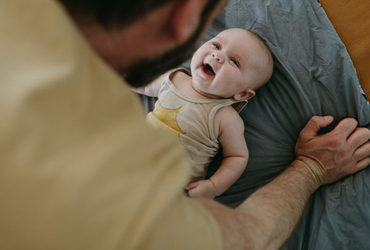 2 månaders bebis på golvet leker med pappa och skrattar