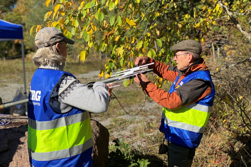 Två personer sätter upp en antenn.