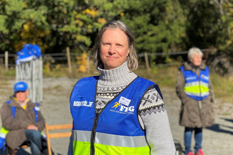 Kvinna i blå/gul väst.