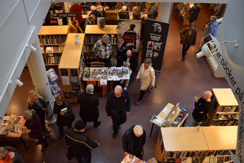 Bild tagen uppifrån. Bilden visar människor på golvet på biblioteket. Runt om finns bokhyllor.