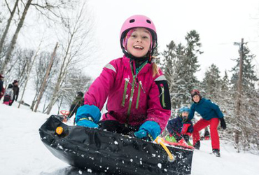 flicka som åker madrass på snön