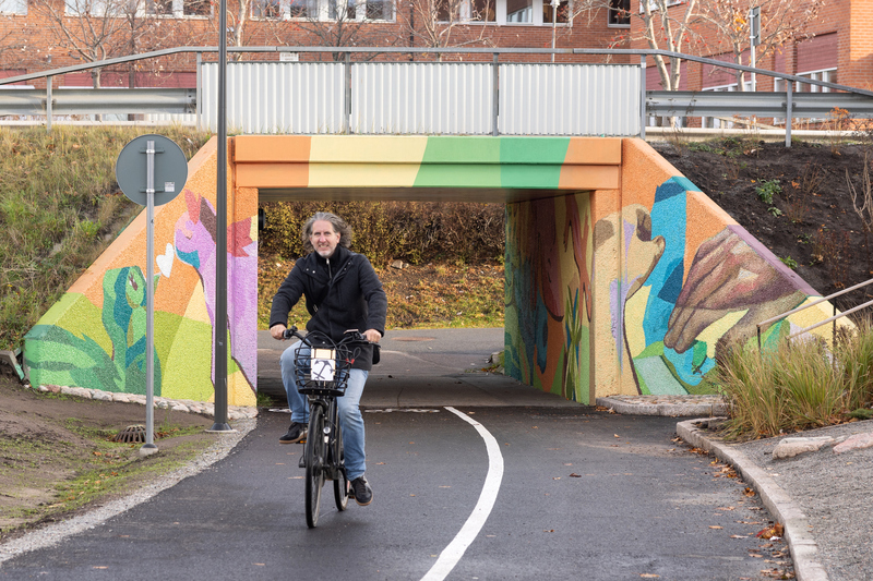 man cyklar genom en färgglad cykeltunnel