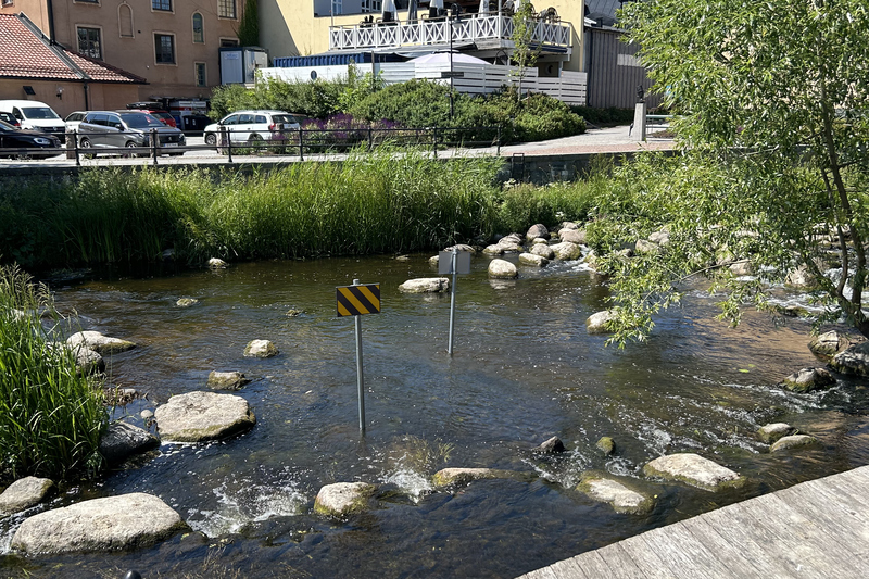 två skyltar med gula och svarta linjer står i Norrtäljeån